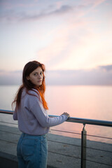 Fototapeta premium Young woman looking at camera in front of the sea at sunrise.