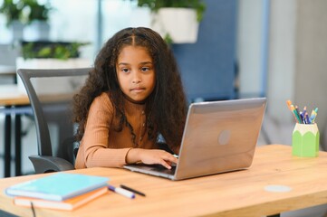 African american girl sitting at table, using laptop for online lesson