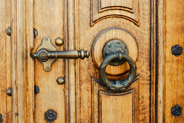 Brown wooden door with two brass knockers. Old elegant metal door handle