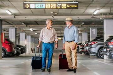 Aged friends walking at airport parking