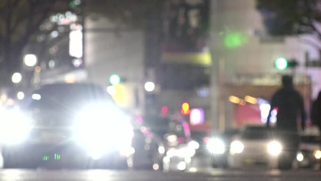 SHIBUYA, TOKYO, JAPAN - NOV 2023 : View of street traffic at night. Many cars, bus, taxi and bike passing by on the road. Japanese transportation and traffic concept video. Out focus shot.