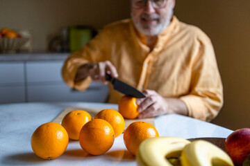 Elderly male cutting oranges at home