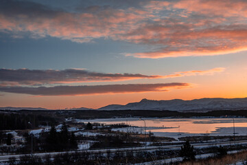 Sunset winter landscape of Reykjavik town suburbs and mountains, Iceland.  Beautiful orange clouds...