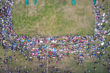 A gathering of people at a summer music festival on the grass. Drone footage.