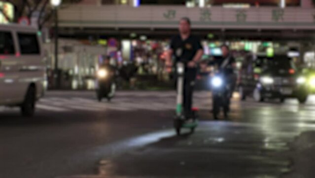 TOKYO, JAPAN - NOV 2023 : View of people riding on rental electric scooter (electric kickboard) at the street. Blurred shot.