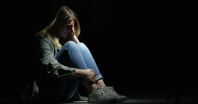 Fear, stress or anxiety with a girl in the dark as a kidnap victim for the crime human trafficking. Sad, scared or crying and an abused youth on a black background with mockup space at night