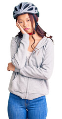 Young beautiful chinese girl wearing bike helmet thinking looking tired and bored with depression problems with crossed arms.