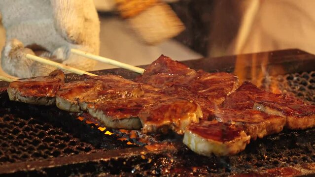 TOKYO, JAPAN - NOV 2023 : View of street food stall selling beef steak on stick at night festival. Japanese food and festival concept video.