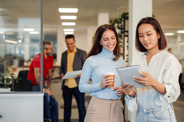 Two multiracial woman having a meeting at office meeting room and using tablet