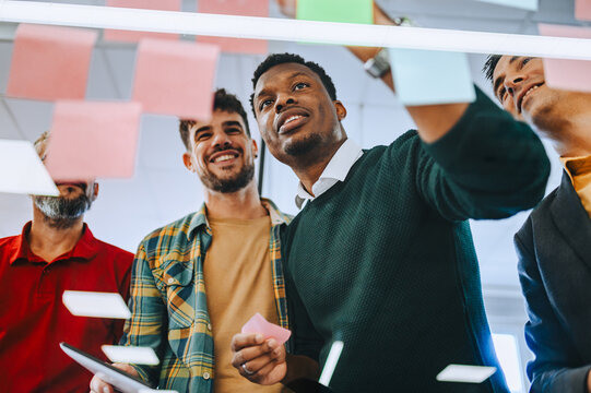 Portrait of a diverse coworkers analyzing tactic while looking at sticky notes. - Powered by Adobe