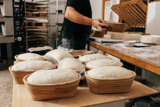 Man covering bread dough in container with plastic
