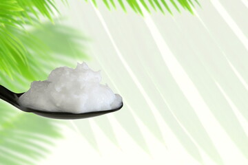 organic coconut cream oil in spoon with coconut blur leaves in white background
