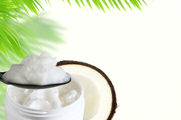 organic coconut cream oil in jar and spoon with dry coconut and leaves in white background