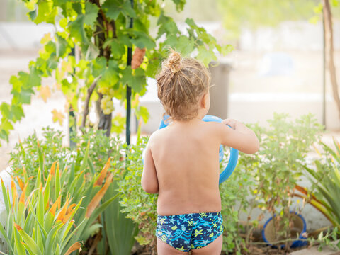 Anonymous Shirtless little boy holding a watering can while standing in garden