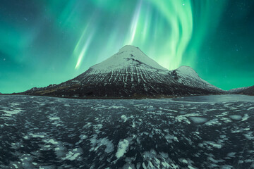 Enchanting northern lights over snow-capped Icelandic peak