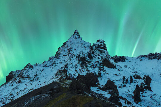 Aurora borealis over a snowy mountain peak in Iceland