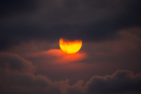 Eerie partial solar eclipse behind dark clouds