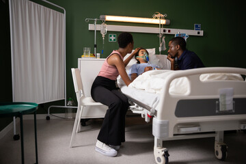 Young African family in hospital sitting near yheir daughter wearing oxygen mask.