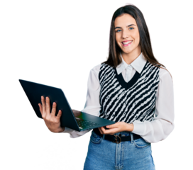 Young brunette teenager working using computer laptop looking positive and happy standing and smiling with a confident smile showing teeth