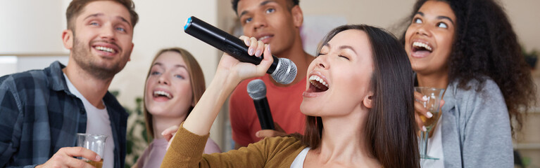 Singing Girl. Young beautiful asian woman holding microphone and singing while having fun with...