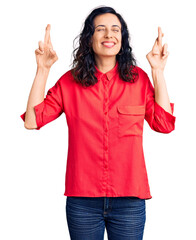 Young beautiful hispanic woman wearing casual clothes gesturing finger crossed smiling with hope and eyes closed. luck and superstitious concept.