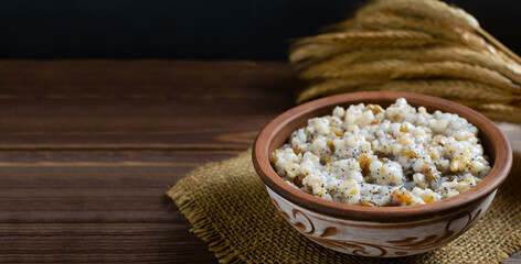 Kutya, a traditional Christmas Ukrainian dish of wheat groats on the table for Christmas or the old new year. Boiled porridge with walnuts, raisins, poppy seeds and honey. Rustic style. Copy space