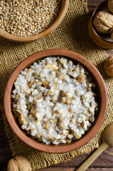 Kutya, a traditional Christmas Ukrainian dish of wheat groats on the table for Christmas or the old new year. Boiled porridge with walnuts, raisins, poppy seeds and honey. Rustic style. Top view
