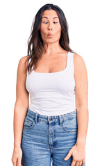 Young beautiful brunette woman wearing casual sleeveless t-shirt making fish face with lips, crazy and comical gesture. funny expression.