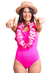 Young beautiful brunette woman wearing swimwear and hawaiian lei approving doing positive gesture...