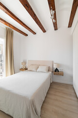 Bed with nightstands and wooden beams in attic bedroom