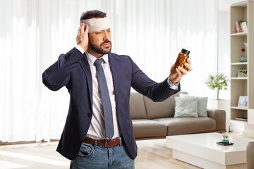 Man with a head injury holding a bottle of medications at home