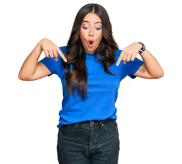 Beautiful brunette young woman wearing casual clothes pointing down with fingers showing advertisement, surprised face and open mouth