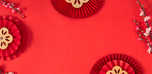 Happy Chinese New Year. Chinese New Year banner with blooming flowers, asian paper fans on red background. Flat lay, top view, copy space