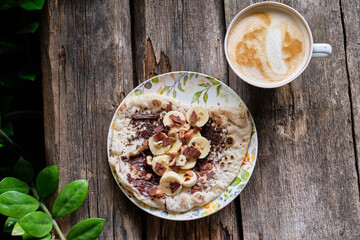 Homemade flatbread with chocolate and bananas on a wooden background.