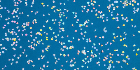 Christmas decor confetti stars on blue background. Xmas, winter, new year concept. Flat lay, top view, copy space