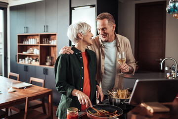 Happy middle aged couple cooking pasta in the kitchen