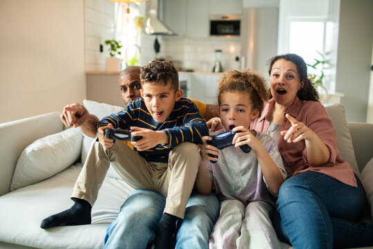 Children playing video games with parents watching at home