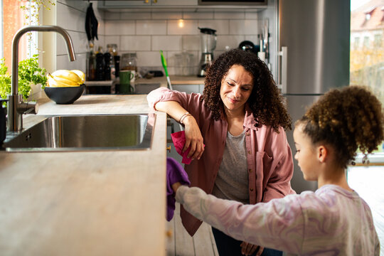 Mother and daughter doing home chores cleaning the kitchen