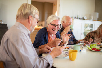 Senior people having breakfast at table in home kitchen