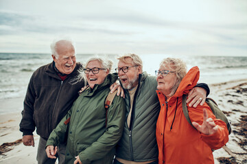 Group of happy senior people on the beach during winter