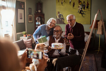 Senior man in wheelchair celebrating birthday with friends at home