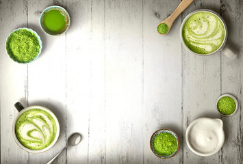 Matcha latte and green tea powder ingredients on warm whte wood background with copy space