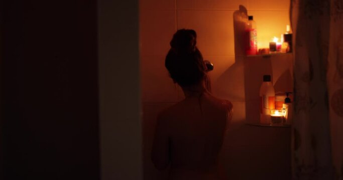 Naked woman taking a shower in candle light, slow motion