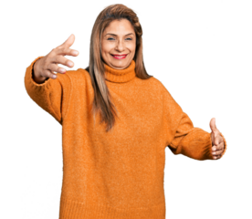 Middle age latin woman wearing turtleneck sweater looking at the camera smiling with open arms for hug. cheerful expression embracing happiness.