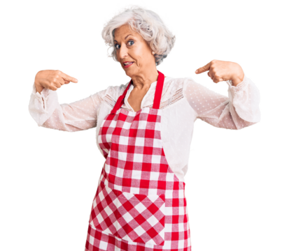 Senior grey-haired woman wearing apron looking confident with smile on face, pointing oneself with fingers proud and happy.