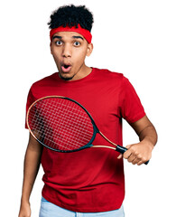 Young african american man wearing tennis player uniform scared and amazed with open mouth for...