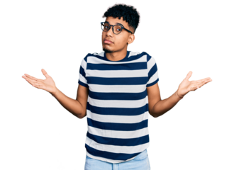 Young african american man wearing casual clothes and glasses clueless and confused expression with arms and hands raised. doubt concept.