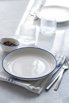 Elegant table setting with crockery and cutlery on light backdrop