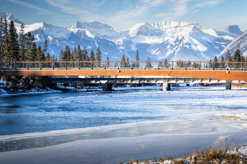 Pedestrian bridge crosses the Bow River overlooking the Canadian Rocky Mountains in Banff Alberta Canada.