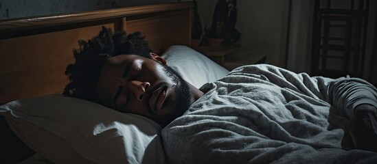 Distressed African American man in bed, struggling with sleep issues after breakup.